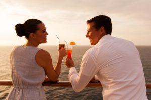 A couple drinking cocktails on a sunset cruise.
