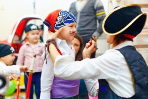 Children dressing up as pirates with drawn-on mustaches.