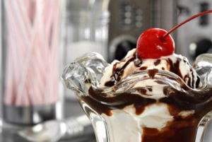 A delicious ice cream sundae with hot fudge and a cherry on top.