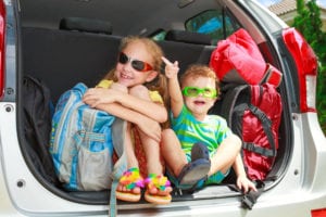 Kids in the back of a car preparing for vacation.